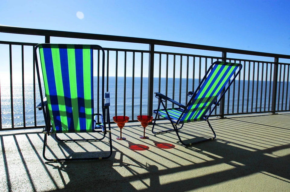Jeune homme souriant en salopette bleue et chemise à carreaux dans un entrepôt de matériaux de construction, tenant des profilés métalliques perforés, faisant un geste positif du pouce levé