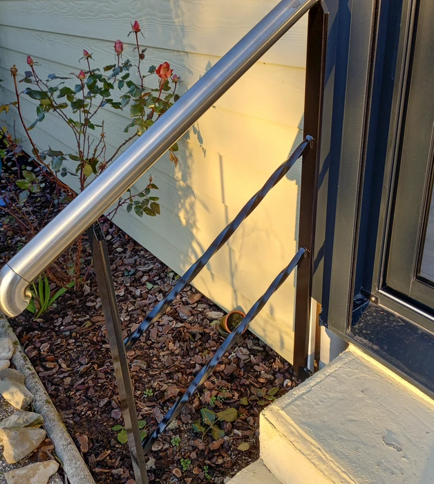 Escalier extérieur métallique avec marches en caillebotis noir fixé sur façade blanche
