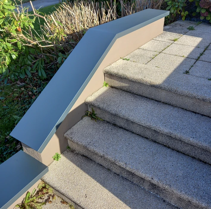 Escalier extérieur métallique avec marches en caillebotis noir fixé sur façade blanche