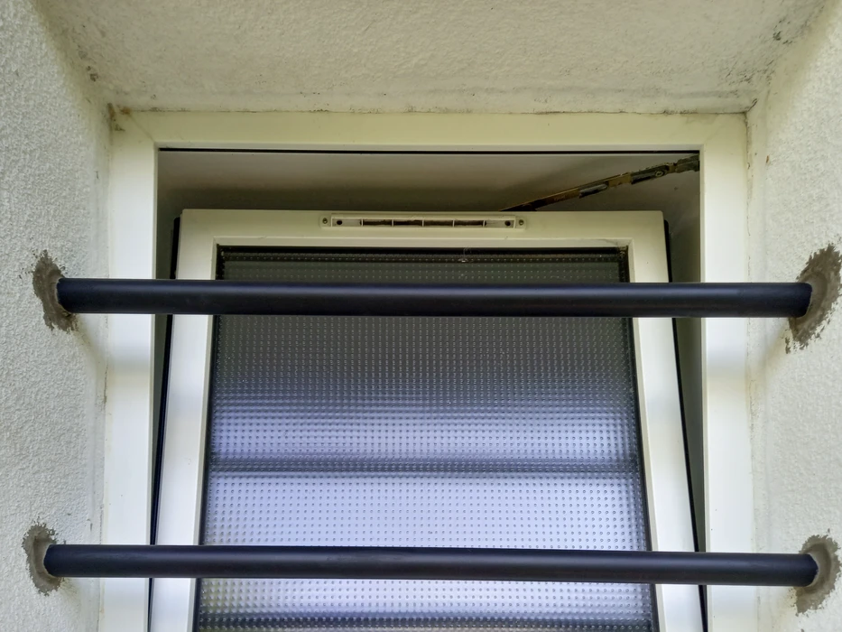 Escalier extérieur métallique avec marches en caillebotis noir fixé sur façade blanche