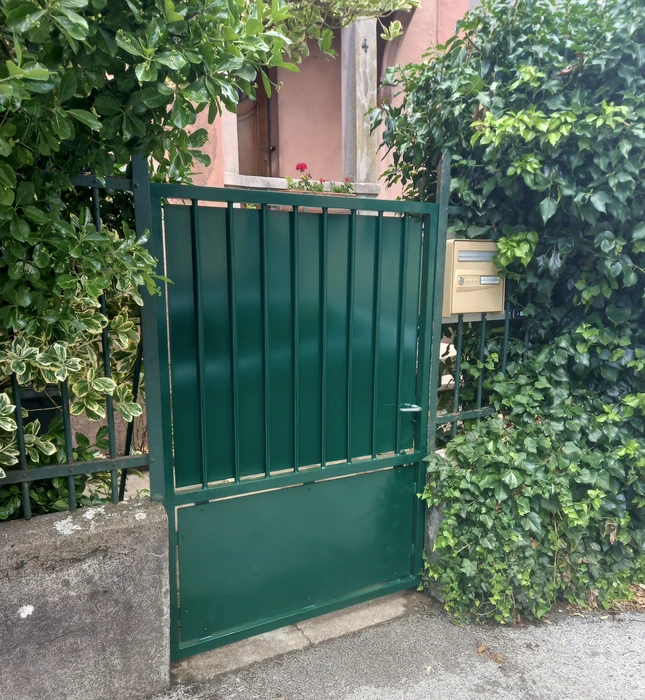 Escalier extérieur métallique avec marches en caillebotis noir fixé sur façade blanche