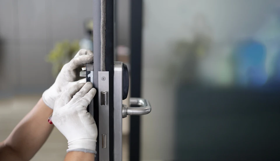 Intérieur d'atelier de serrurier avec cadenas métallique noir au centre, entouré de multiples clés de différents types disposées sur surface en bois