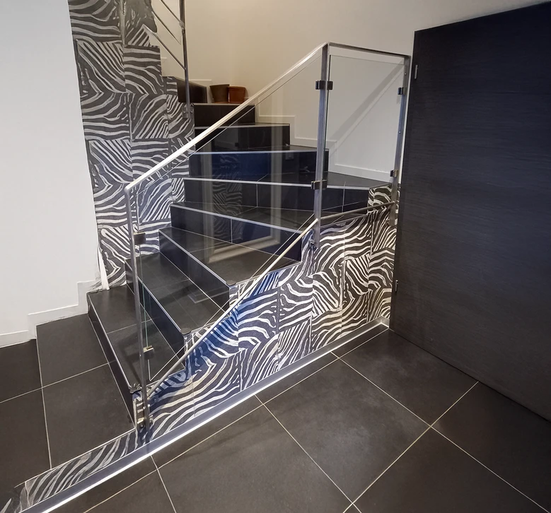 Escalier industriel en acier avec marches caillebotis et limons latéraux, fixé contre mur béton brut